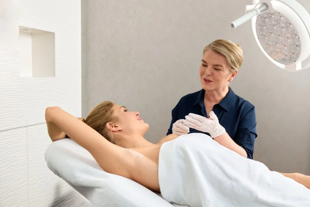 Ärztin der Hamburg Dermatologie behandelt eine Patientin am Hals