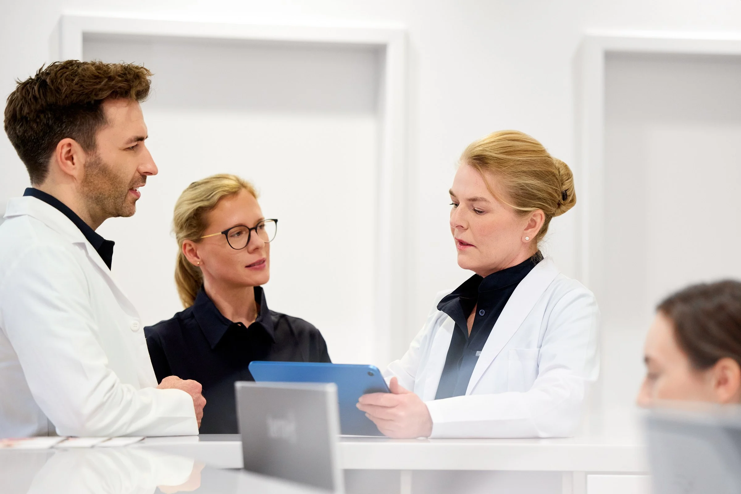 Drei Mitglieder des Teams der Hamburg Dermatologie stimmen sich am Tablet ab