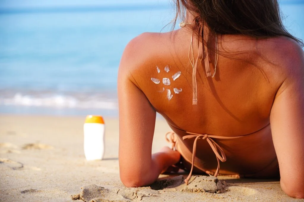 Sonne aus Sonnencreme auf dem gebräunten Rücken einer Frau am Strand
